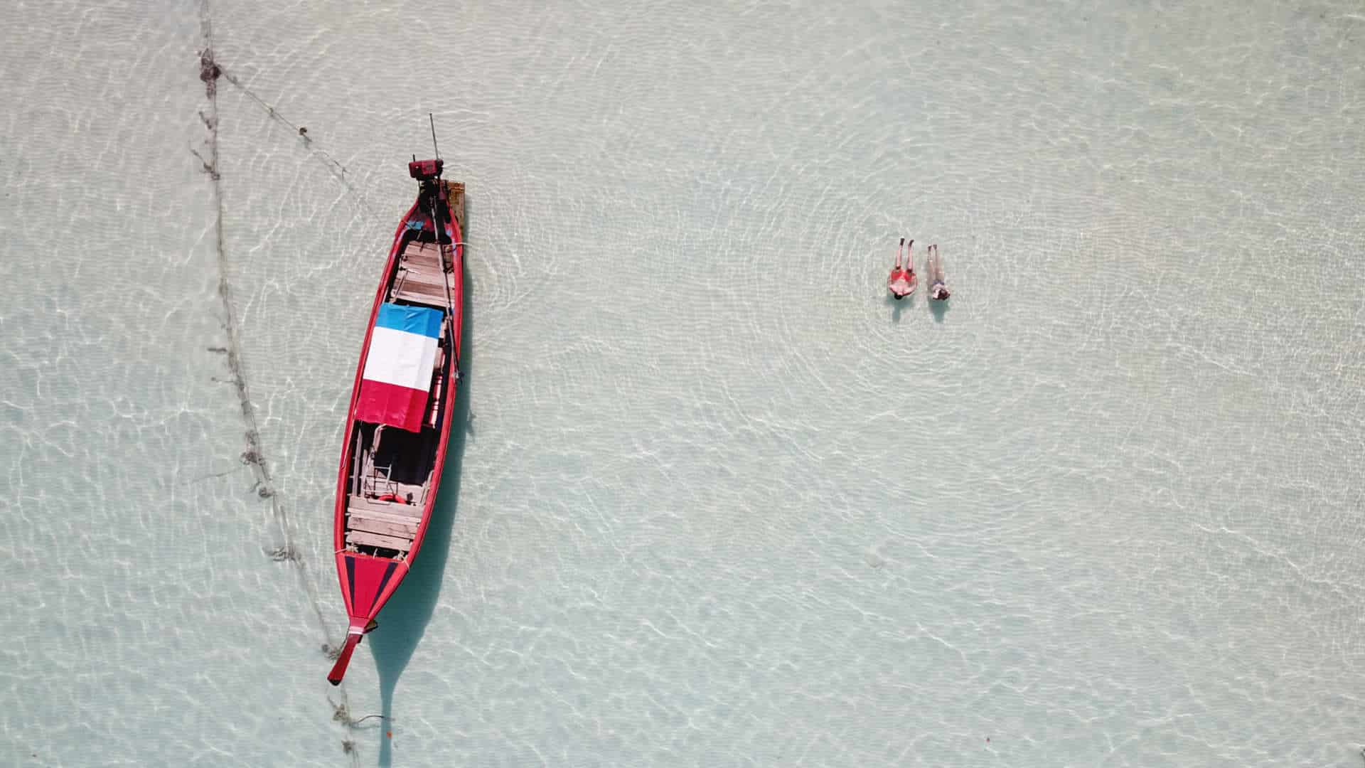 Thailand island traditional boat and swimming couple